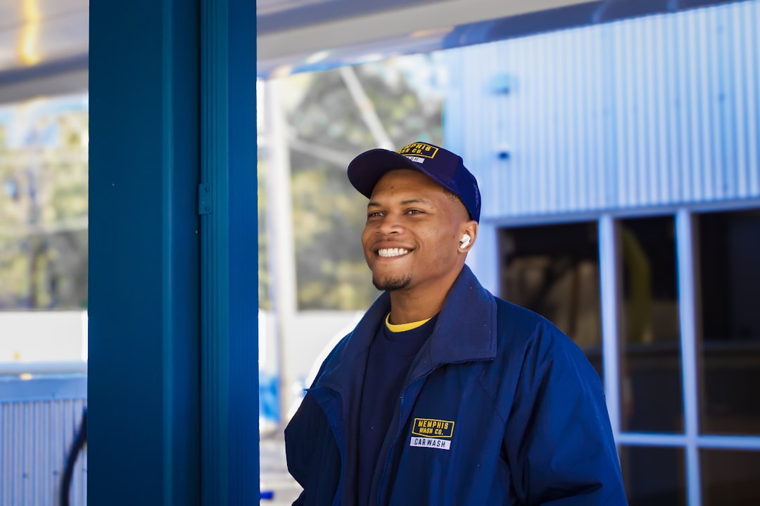 John Matthews, AC Specialist - Professional HVAC technician in blue uniform standing in front of a building