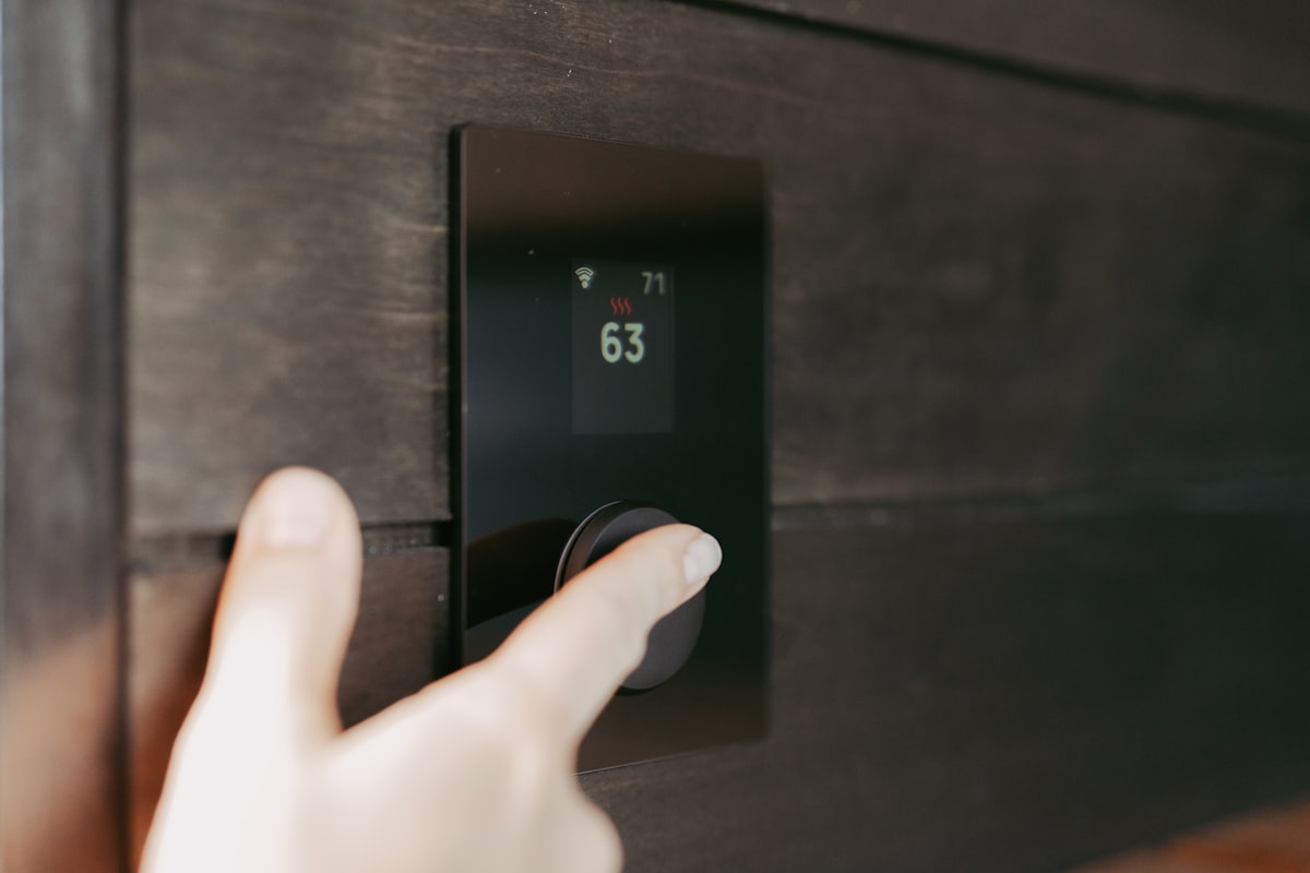 Hand adjusting a modern digital smart thermostat during upgrade installation